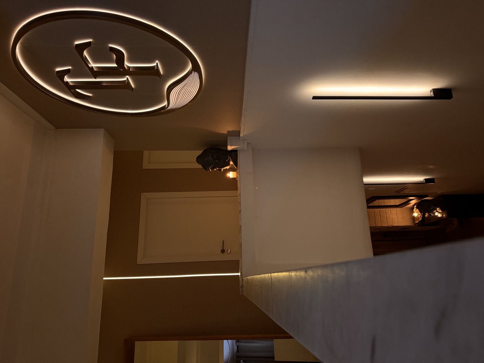 Intimate corridor with illuminated TF logo in The Tantric Flow private space in Lisbon